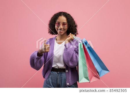 Great shopping. Happy young black woman gesturing thumbs up, holding shopper bag, recommending great sale Great shopping. Happy young black woman gesturing thumbs up, holding shopper bag, recommending great sale 85492305