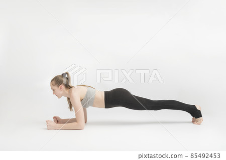 Exercise plank. Young woman doing pilates, working on the abdominal muscles on white background. Girl is engaged. Asana in yoga. 85492453