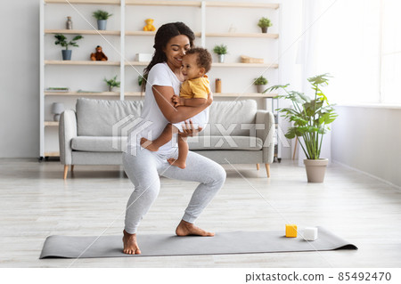 Postpartum Weight Loss. Happy Black Lady Making Squats With Baby On Hands Postpartum Weight Loss. Happy Black Lady Making Squats With Baby On Hands 85492470