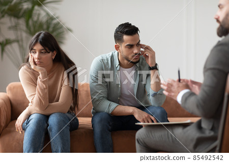 Sad couple sitting at therapy session in therapists office 85492542
