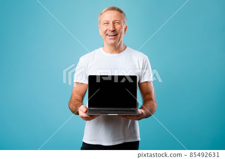 Happy mature man showing black empty pc screen 85492631