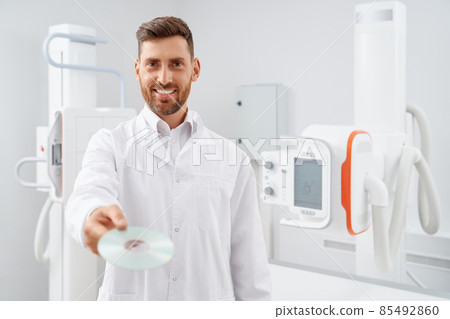 Handsome radiologist showing at camera silver CD plate. 85492860