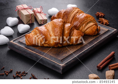 Delicious fresh crispy croissants on a dark concrete background Delicious fresh crispy croissants on a dark concrete background 85493145