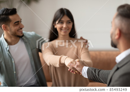 Happy couple shaking hands with therapist at office 85493249