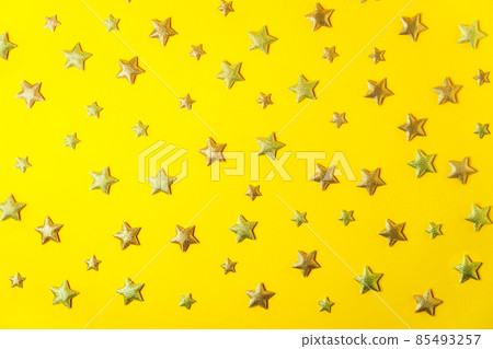 Sparkling and glittering golden stars shape confetti on the bright yellow background. Festive pattern background. Selective focus. Flat Lay, top view. Sparkling and glittering golden stars shape confetti on the bright yellow background. Festive pattern background. Selective focus. Flat Lay, top view. 85493257