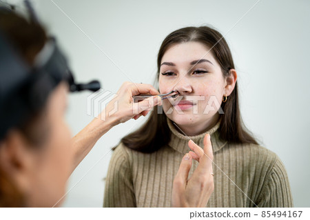 Otolaryngology concept. Positive woman otorhinolaryngologist checking nose with otoscope of his patient at hospital. Nasal congestion, sinusitis, allergy concept. Female patient at modern ENT clinic 85494167