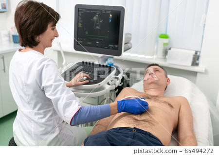Doctor using ultrasound machine to scan heart of a male patient. Cardiologist makes a patient an echocardiographic test in a clinic. Patient under ultrasound examination in the hospital 85494272