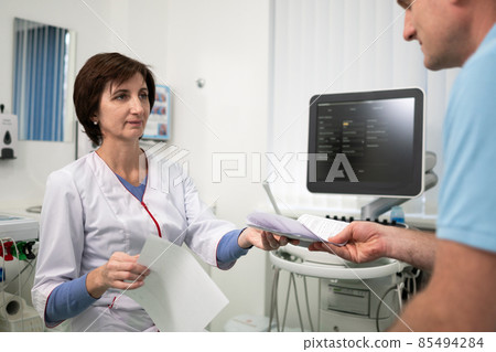 Healthcare and medicine theme. Female general practitioner will see medical tests during health examination of male patient in clinic office. Medical worker in ultrasound diagnostic room with patient 85494284
