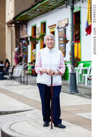 Senior woman at a traditional colorful street in the beautiful colonial town of Salento in the region of Quindio in Colombia 85494315