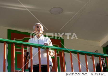 Senior woman at a traditional colorful balcony in the beautiful colonial town of Salento in the region of Quindio in Colombia 85494320
