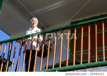 Senior woman at a traditional colorful balcony in the beautiful colonial town of Salento in the region of Quindio in Colombia 85494321