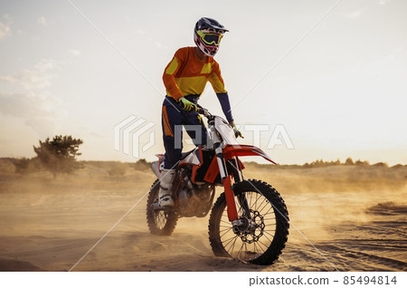 Motocross rider on sportmotor over dust landscape Motocross rider on sportmotor over dust landscape 85494814