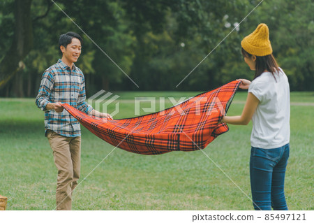 Couple folding a leisure sheet Couple folding a leisure sheet 85497121