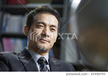 asian corporate executive looking at a turning tellurian with confidence in office asian corporate executive looking at a turning tellurian with confidence in office 85498745