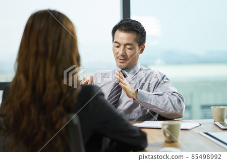 asian businesswoman and businessman discussing business in office 85498992