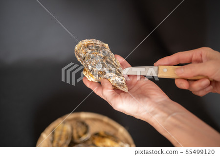 Middle woman trying to open oysters 85499120