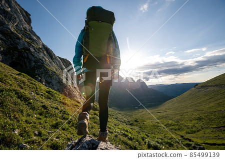 Successful woman backpacker hiking on sunset alpine mountain peak Successful woman backpacker hiking on sunset alpine mountain peak 85499139