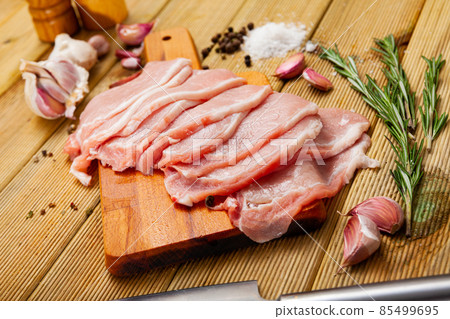 Preparation of raw pork fillet with rosemary and garlic on wooden board Preparation of raw pork fillet with rosemary and garlic on wooden board 85499695