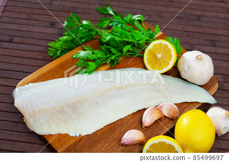 Raw codfish fillet on wooden table with condiments Raw codfish fillet on wooden table with condiments 85499697