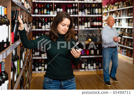 Female customer taking bottle of wine in food shop 85499711