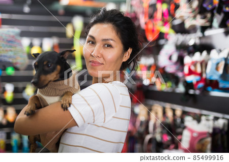 Portrait of smiling woman with his dog in winter clothes visiting pet supplies shop Portrait of smiling woman with his dog in winter clothes visiting pet supplies shop 85499916