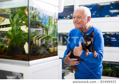 Senior man with dog beside aquarium in pet shop 85499935