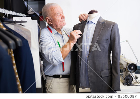 Experienced tailor tries on a new jacket on a mannequin in sewing atelier 85500087
