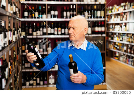 senior man visiting winehouse in search of bottle of good wine senior man visiting winehouse in search of bottle of good wine 85500090