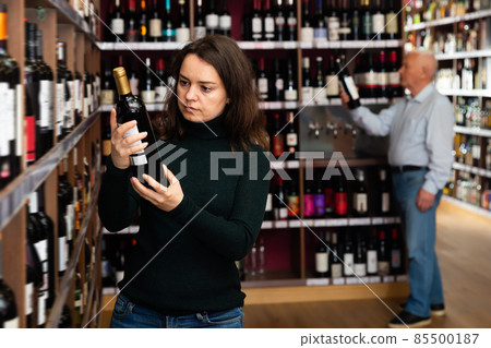Woman customer buying bottle of wine 85500187