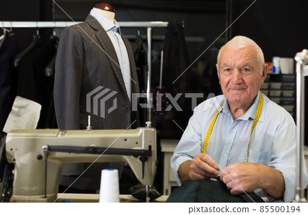 Elderly tailor sews lapel to jacket in his workshop Elderly tailor sews lapel to jacket in his workshop 85500194