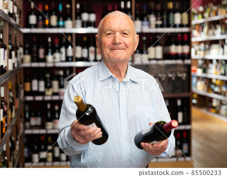 Portrait of senior man visiting winehouse in search of bottle of good wine Portrait of senior man visiting winehouse in search of bottle of good wine 85500233