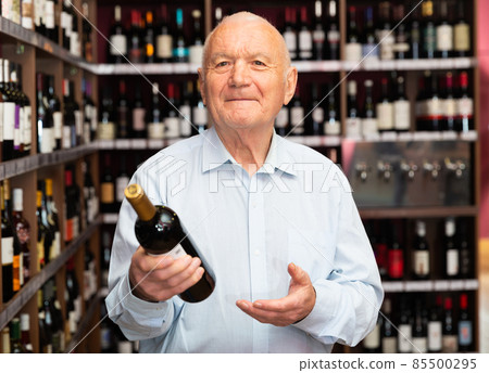 Portrait of senior man visiting winehouse in search of bottle of good wine Portrait of senior man visiting winehouse in search of bottle of good wine 85500295