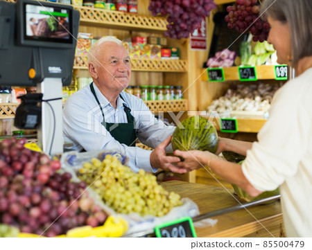 Senior cashier serving customer in greengrocer Senior cashier serving customer in greengrocer 85500479