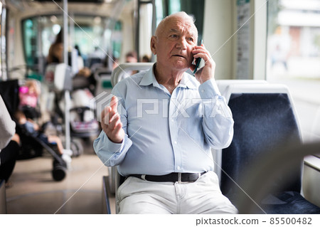 Old man in streetcar talking on phone Old man in streetcar talking on phone 85500482