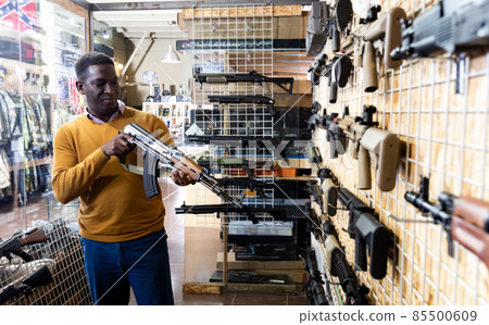 African american guy in military equipment with weapon in army store 85500609