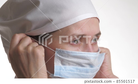 The healthcare professional puts on a mask and smiles. Medical staff close-up portrait. Woman in protective mask.Isolated on white background. Health care and medical concept. Close-up 85501517
