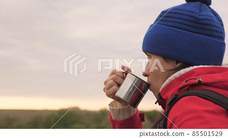 The girl drinks tea from a mug sitting on a high mountain and enjoying nature in the park. Woman traveler looking for adventure. Relax on the hike. Long distance hiking trips. Human explorer of The girl drinks tea from a mug sitting on a high mountain and enjoying nature in the park. Woman traveler looking for adventure. Relax on the hike. Long distance hiking trips. Human explorer of 85501529