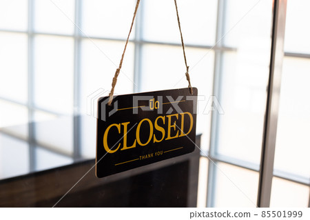 Close-up of a closed sign hanging on a glass door. Close-up of a closed sign hanging on a glass door. 85501999