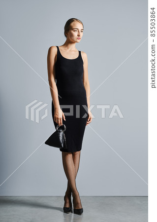 Full length portrait of strict and detached woman posing with hand bag Full length portrait of strict and detached woman posing with hand bag 85503864