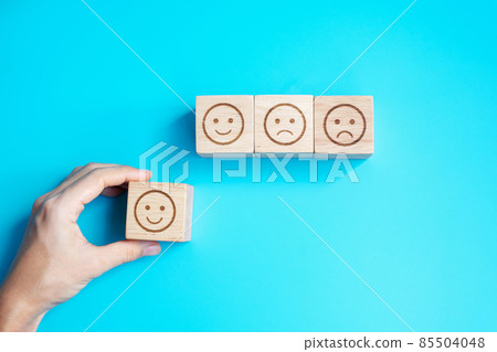 Man hand holding emotion face block. Customer choose Emoticon for user reviews. Service rating, ranking, customer review, satisfaction, evaluation and feedback concept Man hand holding emotion face block. Customer choose Emoticon for user reviews. Service rating, ranking, customer review, satisfaction, evaluation and feedback concept 85504048