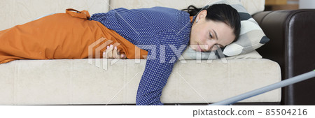 Tired woman lies on couch after cleaning apartment Tired woman lies on couch after cleaning apartment 85504216