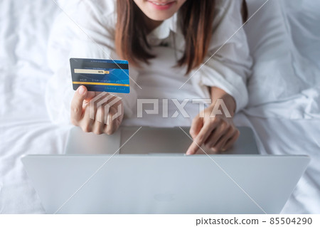 woman using computer laptop and credit card for online shopping while making order on bed in morning at home. technology, ecommerce, digital banking online payment and apartment living concept woman using computer laptop and credit card for online shopping while making order on bed in morning at home. technology, ecommerce, digital banking online payment and apartment living concept 85504290