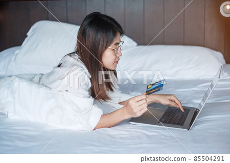 woman using computer laptop and credit card for online shopping while making order on bed in morning at home. technology, ecommerce, digital banking online payment and apartment living concept woman using computer laptop and credit card for online shopping while making order on bed in morning at home. technology, ecommerce, digital banking online payment and apartment living concept 85504291