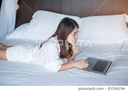 Happy woman using laptop for work, female meeting online by computer notebook on bed. technology, network, work from home, lifestyle and digital communication concept Happy woman using laptop for work, female meeting online by computer notebook on bed. technology, network, work from home, lifestyle and digital communication concept 85504294