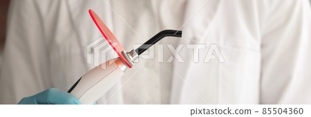 Dentist doctor holds curing light in hand 85504360