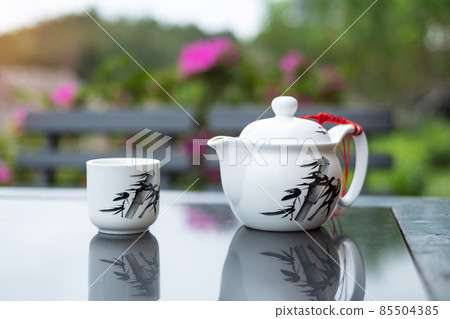 teapot and hot tea to cup on wood table against tea garden view background in the morning, Ban Rak Thai village, Mae Hong Son province, Thailand teapot and hot tea to cup on wood table against tea garden view background in the morning, Ban Rak Thai village, Mae Hong Son province, Thailand 85504385