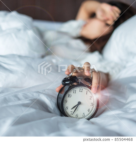 Asian woman lying in bed at morning with retro alarm clock, young female sleep in bedroom at home. restless, insomnia sleeping, worried and stressed concepts Asian woman lying in bed at morning with retro alarm clock, young female sleep in bedroom at home. restless, insomnia sleeping, worried and stressed concepts 85504468