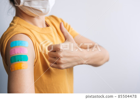 woman showing Thumb sign with bandage after receiving covid 19 vaccine. Vaccination, herd immunity, side effect, booster dose, vaccine passport and Coronavirus pandemic 85504478