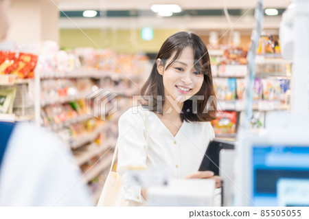 Young woman using smartphone payment at supermarket Young woman using smartphone payment at supermarket 85505055