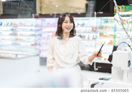 Young woman using smartphone payment at supermarket Young woman using smartphone payment at supermarket 85505065